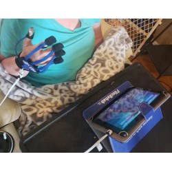 Skupiona kobieta po udarze, ćwiczy rękawicą MusicGlove przy tablecie.